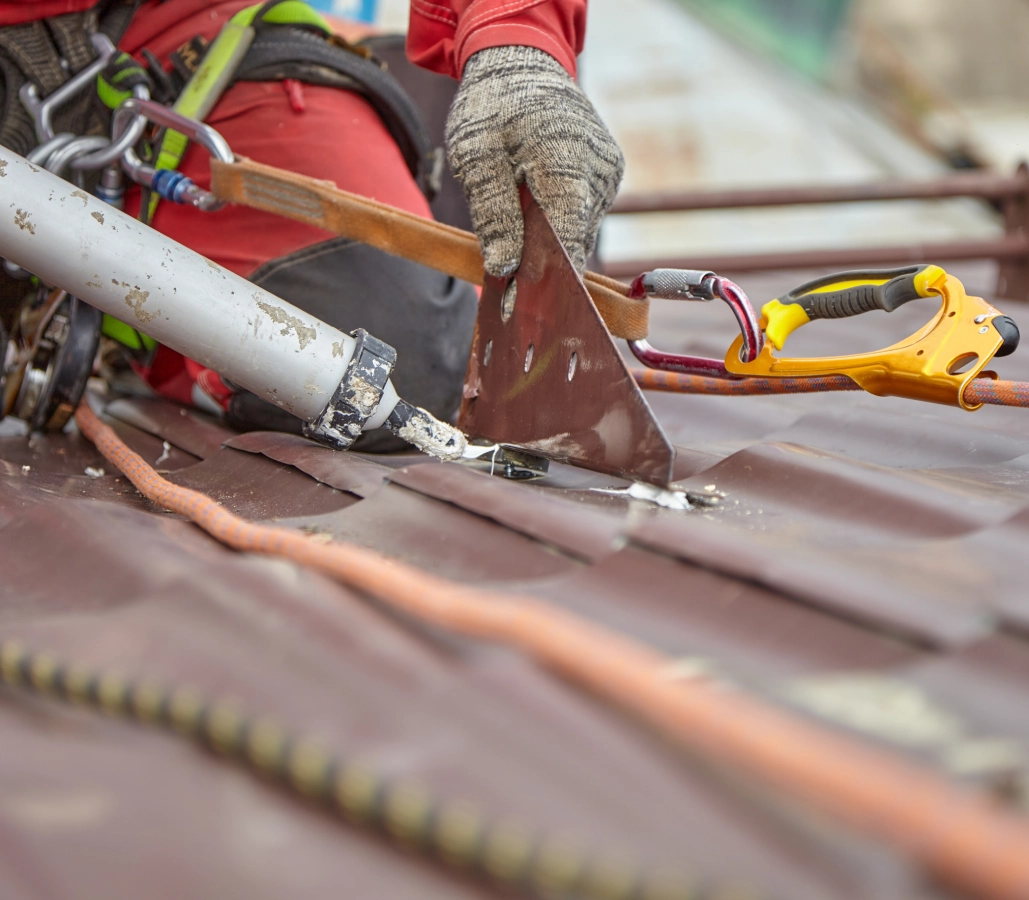 Roofer applying sealant to metal roof.