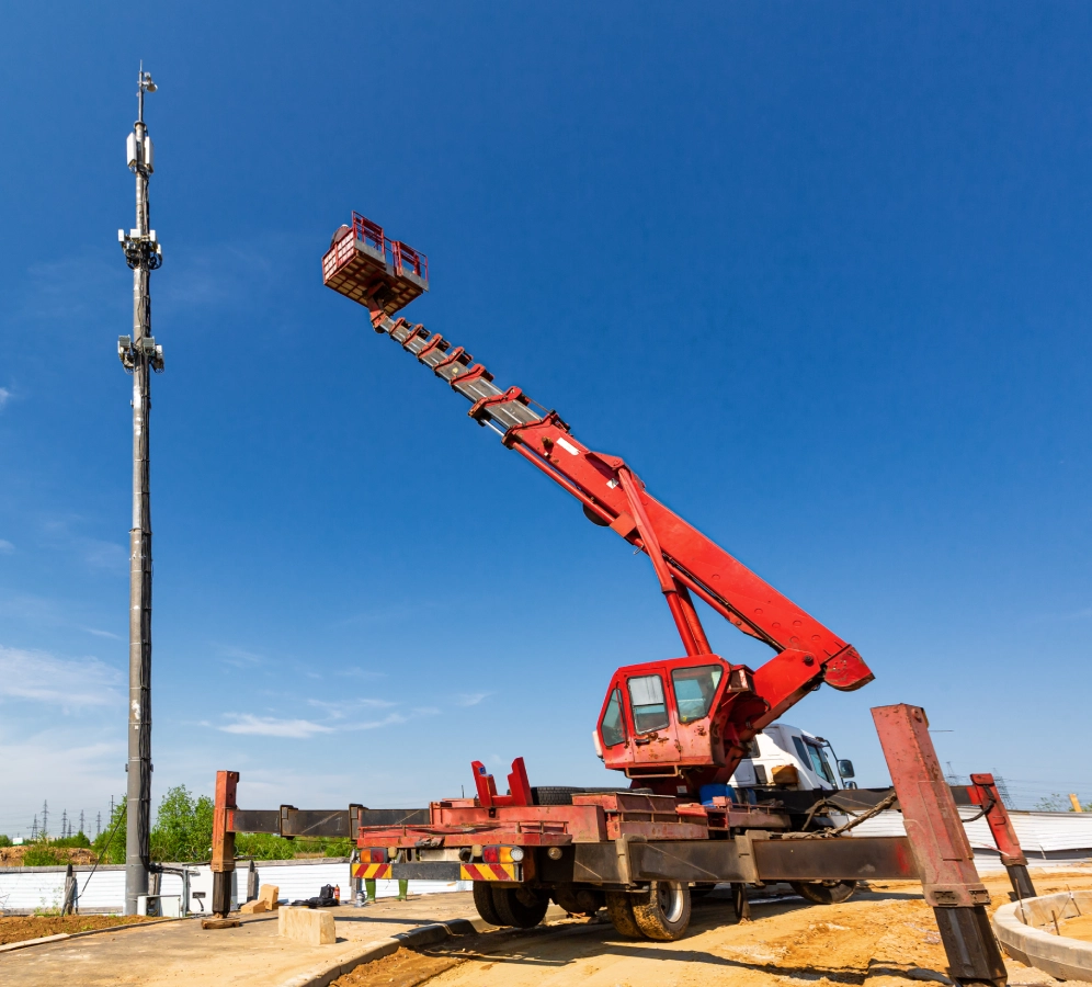 Crane lifting worker toward communication tower.